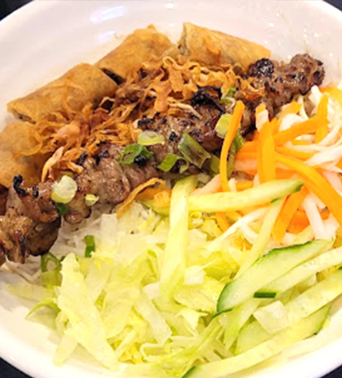Grilled pork vermicelli bowl with vegetables and spring rolls